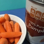 Carrots in a bowl next to a can of pumpkin