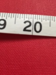 A flexible tape measure shows 20 inches against a red background